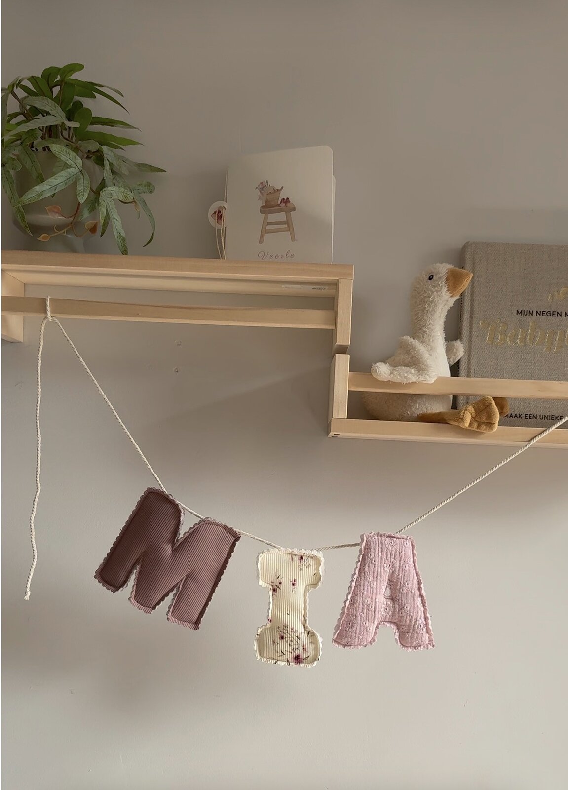 Namensgirlande aus Stoff mit dem Namen Mia in altrosa Ripp, Blumenprint und rosa Lochstickerei, im Kinderzimmer aufgehängt
